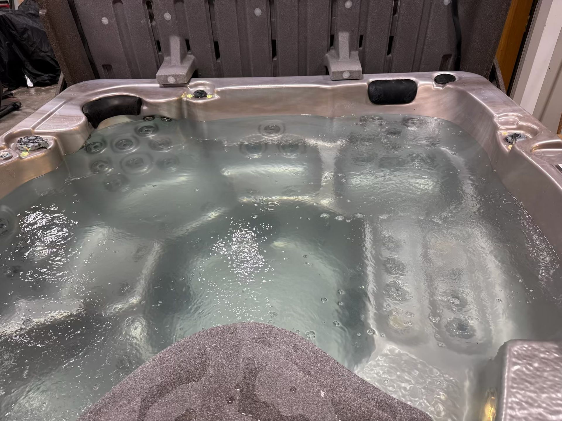 Hot tub filled with water, jets on. Gray stone in foreground.