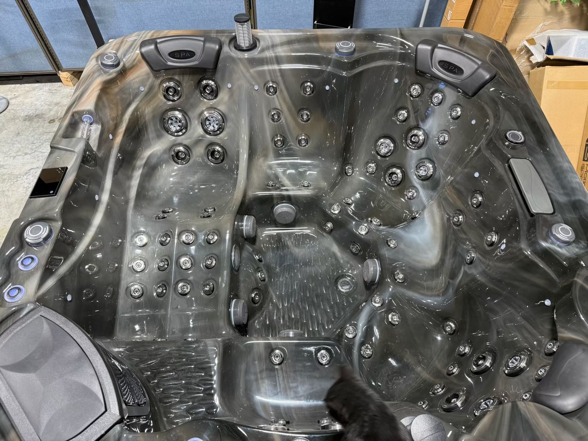 Dark gray hot tub with multiple jets and control panels, top-down view.