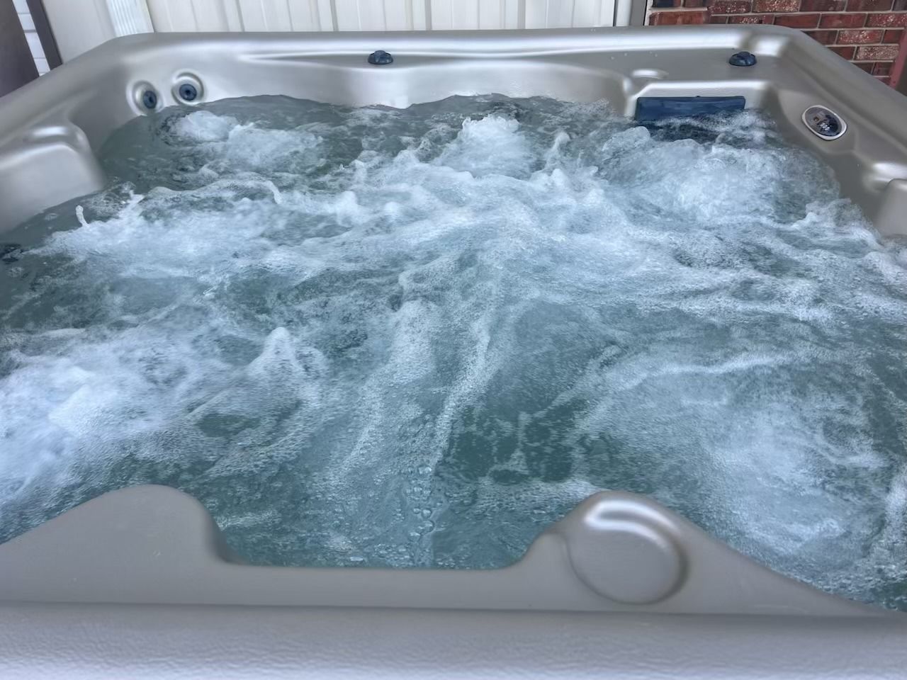 Hot tub filled with bubbling water; beige interior.
