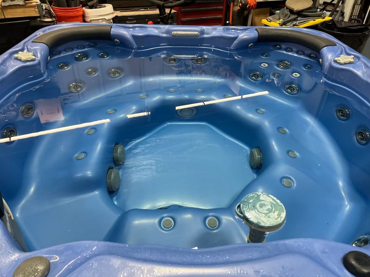 Blue hot tub interior with jets, partially filled with water, in an indoor setting.