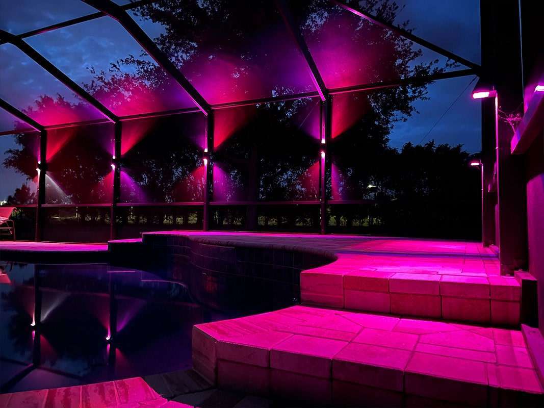 Purple-lit outdoor lounge with curved canopy, steps, and seating at dusk