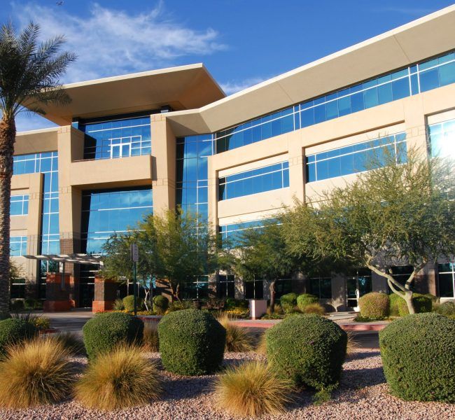 A large building with lots of windows and bushes in front of it