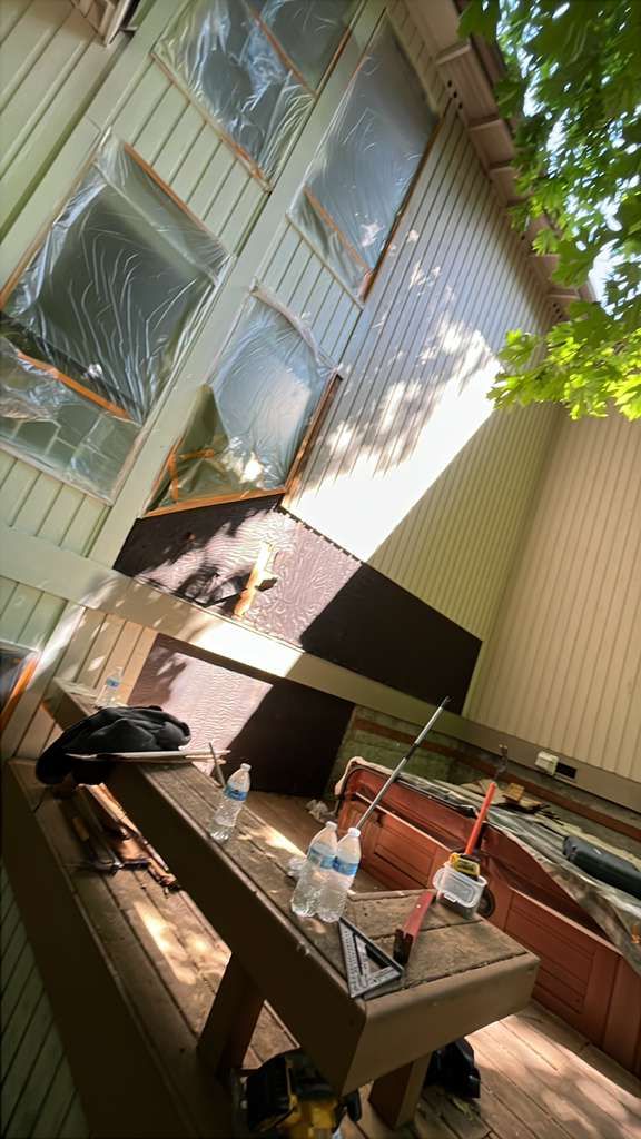 Sunlit patio with wooden table, benches, and a black-and-white dog lounging by a modern building