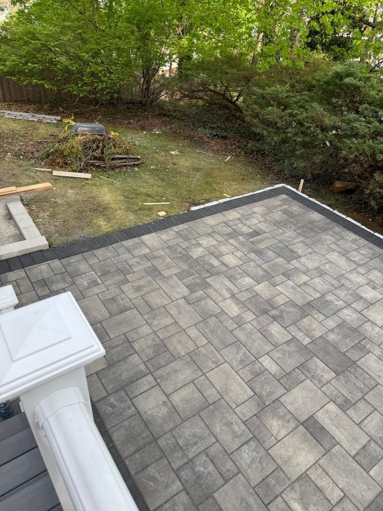 Backyard patio with gray pavers beside a grassy yard and trees