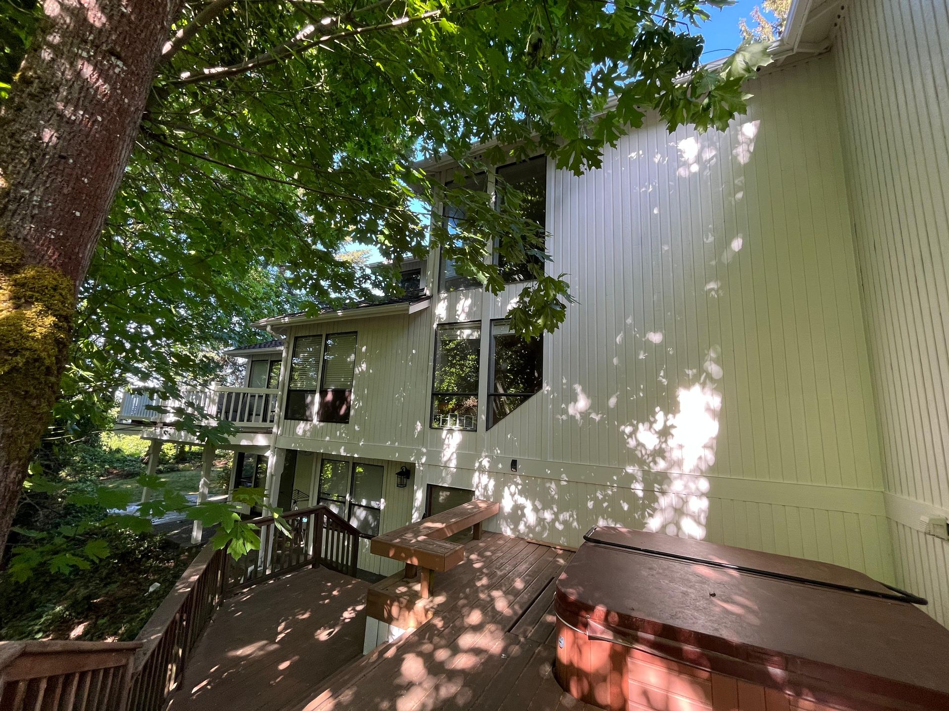 Wooded apartment deck with red benches and a white building wall in dappled sunlight
