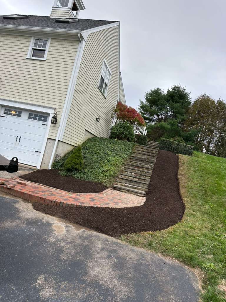 House with fresh mulch landscaping along a sloped driveway and walkway under overcast skies